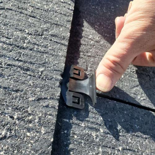 タスペーサーをスレート瓦の隙間に挿入する縁切り作業の写真